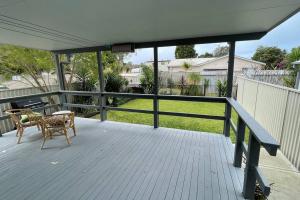 a porch with a table and a chair on it at Budgie Bungalow - Pet friendly family home in Budgewoi