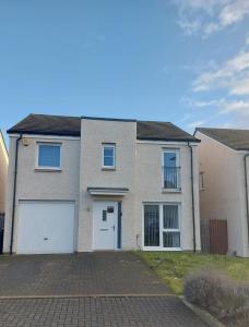 a brick house with a white garage at Beautiful 4-Bedroom House with Private Garden & Parking in Edinburgh