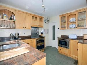 a large kitchen with wooden cabinets and a sink at Carreg Yr Eos - Cottage in Fishguard