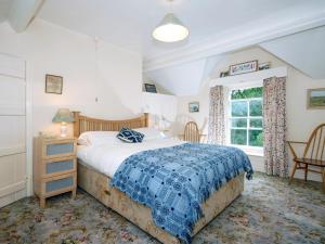 a bedroom with a bed with a blue blanket and a window at Carreg Yr Eos - Cottage in Fishguard