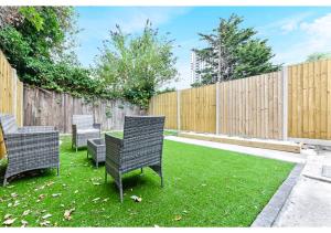 a backyard with chairs and a table and a fence at Tranquility in Bloom: Refreshing 2BR Apartment in London