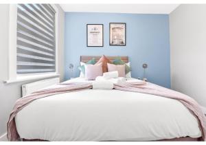 a bedroom with a large white bed with blue walls at Tranquility in Bloom: Refreshing 2BR Apartment in London