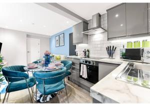 a kitchen with a table and some blue chairs at Tranquility in Bloom: Refreshing 2BR Apartment in London