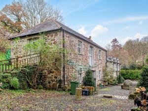 uma antiga casa de pedra com um jardim em frente em Hallowarren Barn em Saint Anthony