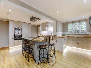 a kitchen with white cabinets and bar stools at Rod Line Cottage in Croft