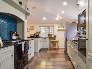 a large kitchen with white cabinets and appliances at Flanders Cottage in Lymington