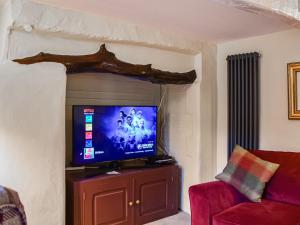 a living room with a flat screen tv on a cabinet at Flanders Cottage in Lymington