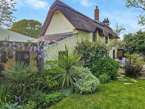 a cottage with a thatched roof and plants at Flanders Cottage in Lymington