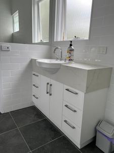 a white bathroom with a sink and a mirror at Cordova - Perfect Summer or Winter Getaway in Merimbula +45 photos