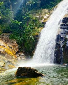 una cascada en un río con una roca en el agua en Aconchego 3 dorms, piscina, churrasq em Condomínio Fechado, en Boicucanga