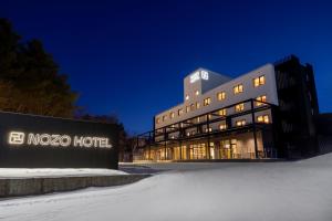 富良野Nozo Hotel的夜间雪中一家诺索酒店