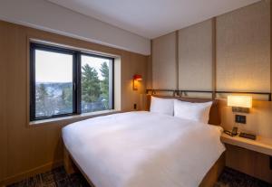 富良野Nozo Hotel的带窗户的房间里有一张白色的大床