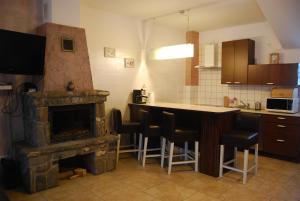 a kitchen with a fireplace and a bar with stools at Apartaments Gory in Niedzica Zamek