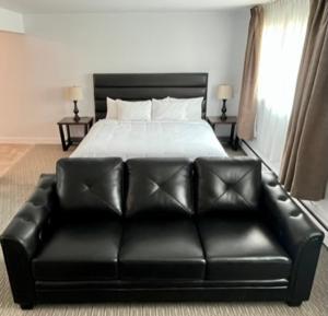 a black leather couch in a bedroom with a bed at Anavada Inn & Suites - Prince George in Prince George
