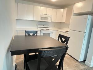 a kitchen with a table and a white refrigerator at Anavada Inn & Suites - Prince George in Prince George