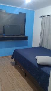 niebieski pokój z łóżkiem i telewizorem z płaskim ekranem w obiekcie Casa sambaqui w mieście Florianópolis