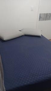 niebieskie łóżko z białą poduszką na górze w obiekcie Casa sambaqui w mieście Florianópolis