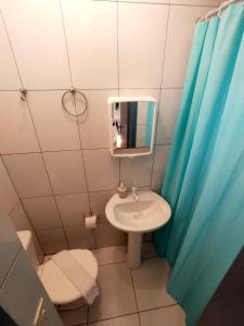 a bathroom with a sink and a toilet and a mirror at Areias do Sol Suítes in Florianópolis