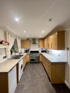 una cocina con armarios de madera y electrodomésticos blancos en Entire 3 bedroom end of terrace house!, en Thamesmead