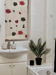 La salle de bains est pourvue d'un lavabo blanc et d'une peinture florale sur le mur. dans l'établissement Entire 3 bedroom end of terrace house!, à Thamesmead