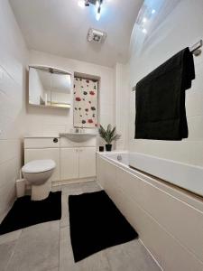 La salle de bains blanche est pourvue de toilettes et d'un lavabo. dans l'établissement Entire 3 bedroom end of terrace house!, à Thamesmead