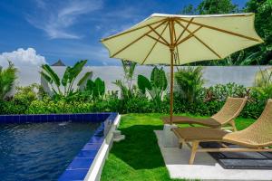 an umbrella and chairs next to a swimming pool at Villa Primarosa - Charming 2BR Villa in Pererenan in Munggu