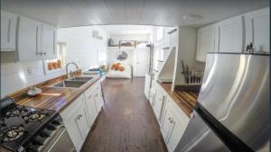 cocina con armarios blancos y nevera de acero inoxidable en 108 Tiny House Bradenton en Bradenton