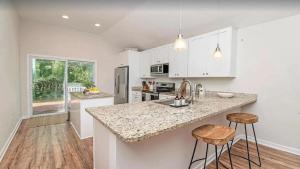 a kitchen with white cabinets and a counter with stools at Bright 3BR Cottage near the Beach and Downtown in Saint Augustine