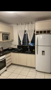 a kitchen with a white refrigerator and a window at Apartamento próximo do aeroporto internacional in São José dos Pinhais