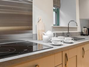 a kitchen counter with cups and saucers on it at The Old Mill - Uk45931 in Linlithgow