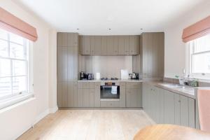 uma cozinha com armários cinzentos e uma bancada em Luxurious 3BD Flat - Sloane Square Chelsea! em Londres