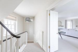 uma escada branca numa sala de estar com paredes brancas em Luxurious 3BD Flat - Sloane Square Chelsea! em Londres