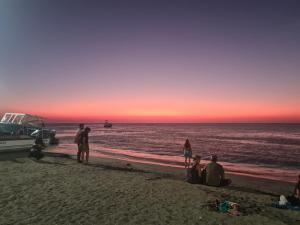 un gruppo di persone seduti sulla spiaggia al tramonto di Hostal Casa Yare a Rodadero