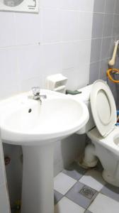 a bathroom with a white sink and a toilet at Kuhara Court Apartment Suite in Tawau