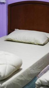 a bed with two white pillows and a wooden headboard at Kuhara Court Apartment Suite in Tawau