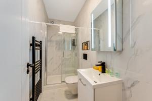 a white bathroom with a shower and a sink at Bright and Relaxing One Bedroom Flat in London