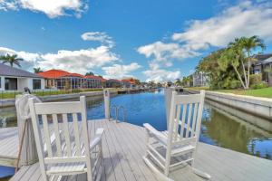 two white chairs sitting on a dock next to a river at 80 Marco Island in Marco Island