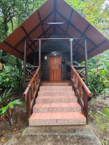 a small building with a wooden door and stairs at Evergreen Lodge in Tortuguero