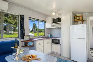 a kitchen with a white refrigerator and a table at MGM Studio Cabin - Himitangi Holiday Studio in Foxton