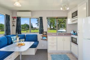 a kitchen with a blue couch and a table at MGM Studio Cabin - Himitangi Holiday Studio in Foxton
