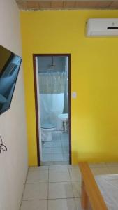 a bathroom with a toilet and a yellow wall at Suíte em Cumuruxatiba beira-mar in Cumuruxatiba
