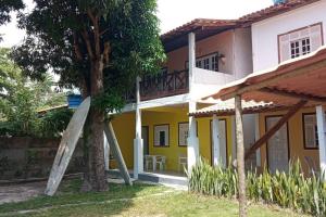 una casa amarilla y blanca con un árbol y una escalera en Suíte em Cumuruxatiba beira-mar en Cumuruxatiba