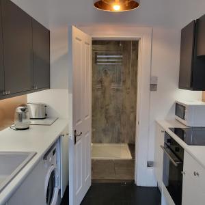 a kitchen with a shower with a man standing in the shower at 10 Large Elegant Studio - Prime Location - Comfortable - Private in Brighton & Hove