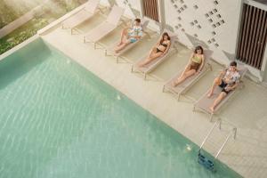 three women sitting in chairs next to a swimming pool at Pranakorn Heritage Hotel in Bangkok
