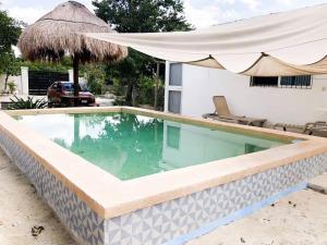 uma piscina com um guarda-sol ao lado de uma casa em Hermosa Casa en Chelem A 5 min Caminando de Playa em Chelem
