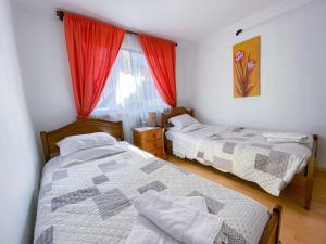 a bedroom with two beds and a window with red curtains at Hostal Alcala in Temuco