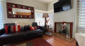 uma sala de estar com um sofá de couro preto e um espelho em Hostal Alcala em Temuco