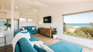 a living room with a blue couch and a large window at Dolphinview in Coffin Bay