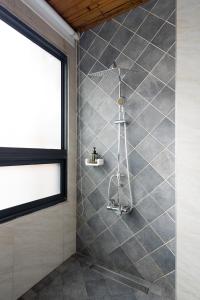 a shower in a bathroom with a gray tiled wall at Songyuan 68 Villa in Hualien City