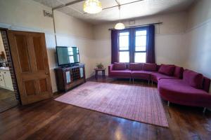 un salon avec un canapé violet et une télévision dans l'établissement Whispering Pines, à Albany